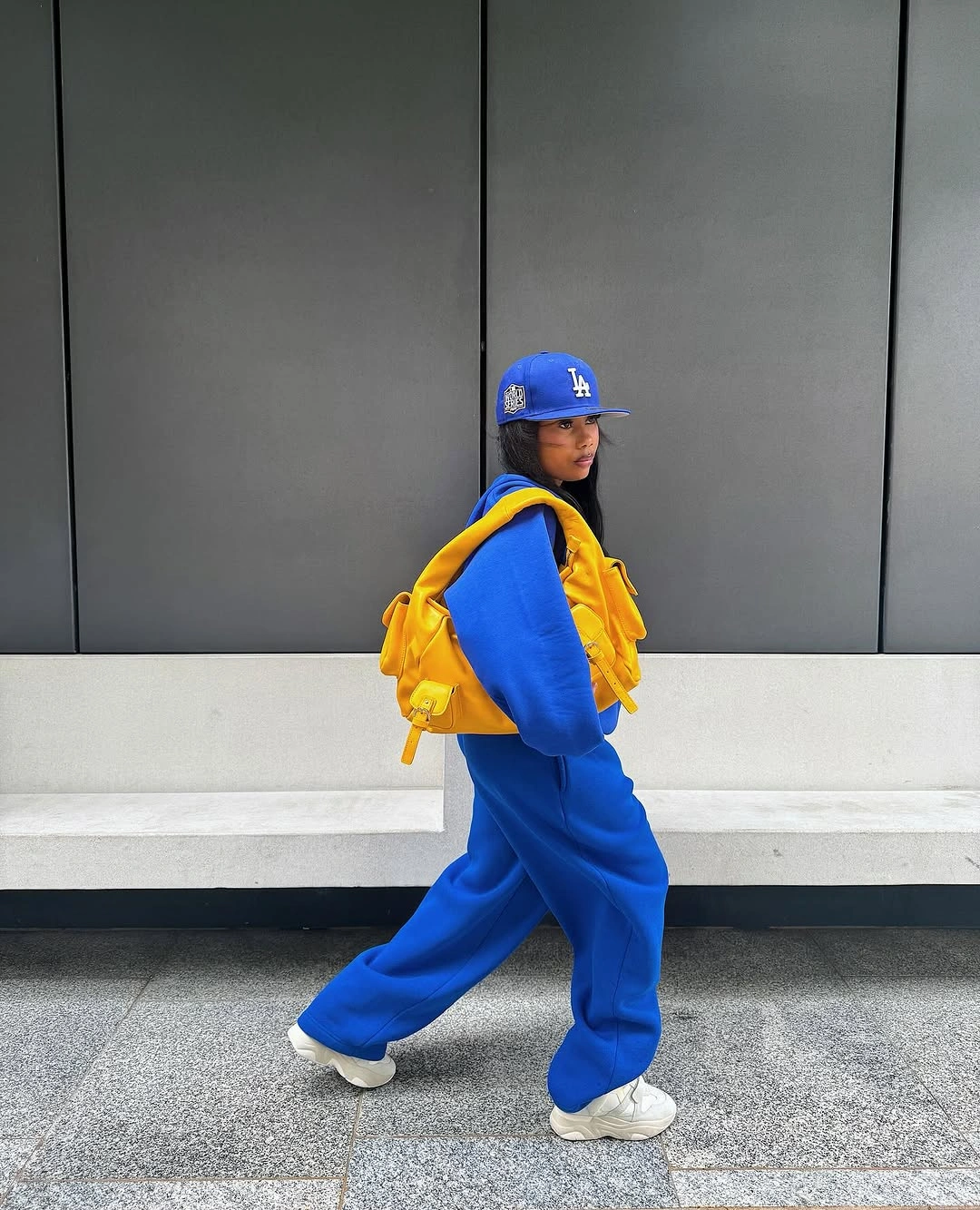 Cobalt tracksuit with yellow puffer vest, cap, and white sneakers