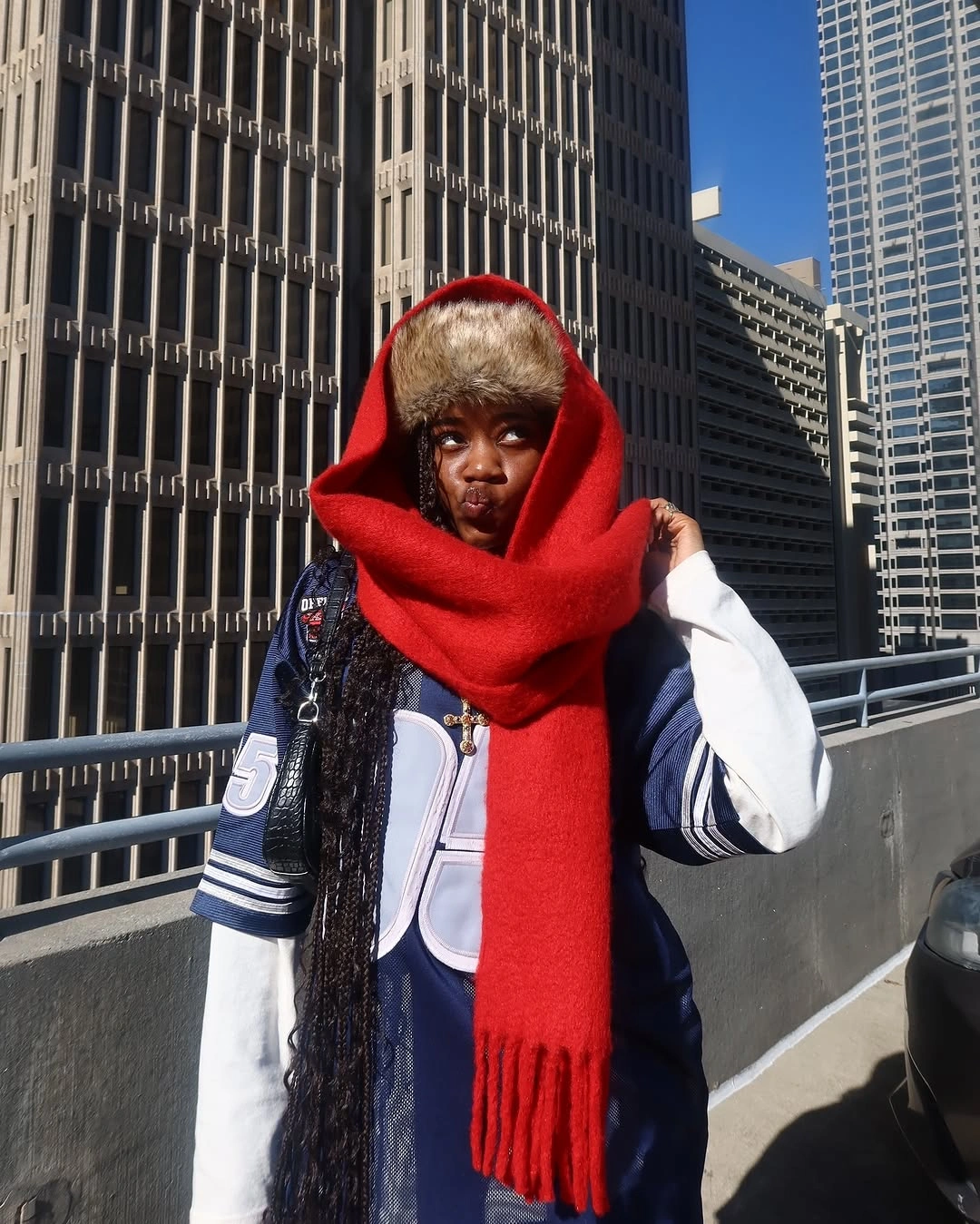Navy and white varsity jacket with oversized red scarf and dark jeans