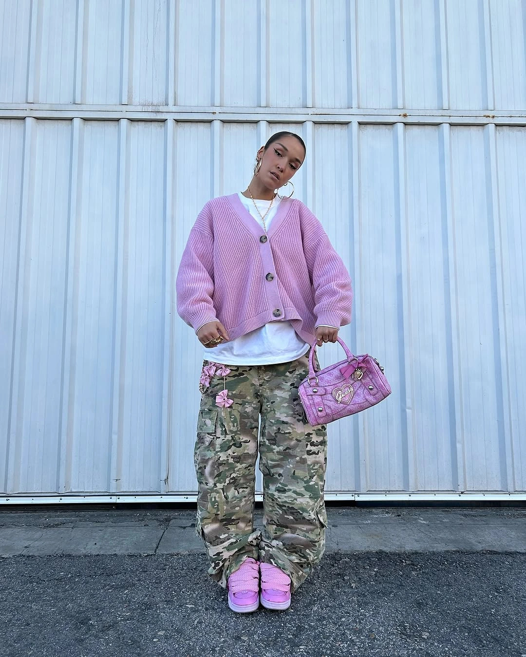 Pink cardigan with camouflage cargo pants, lavender bag, and pink shoes