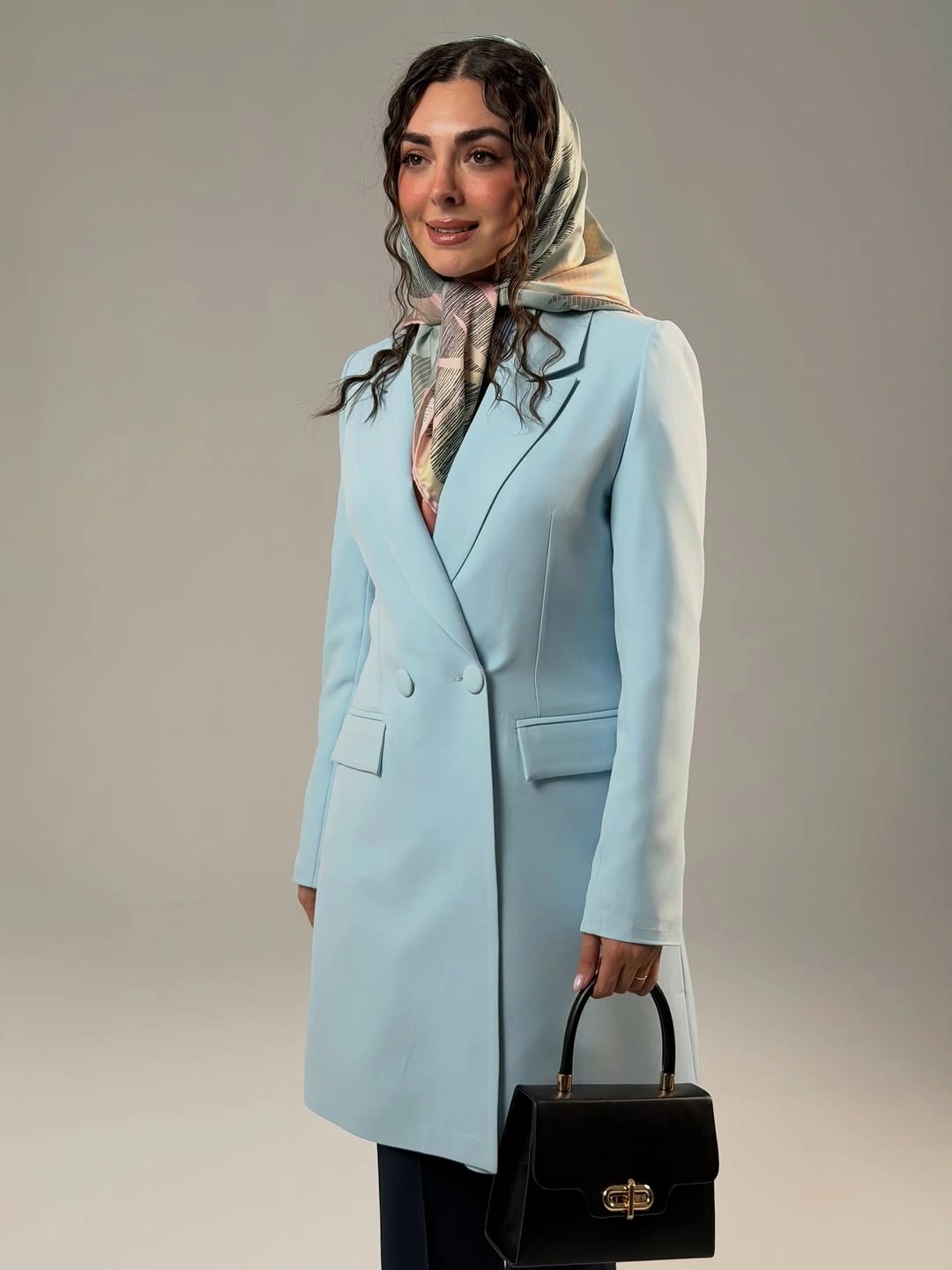 Powder blue tailored coat with patterned scarf and black handbag