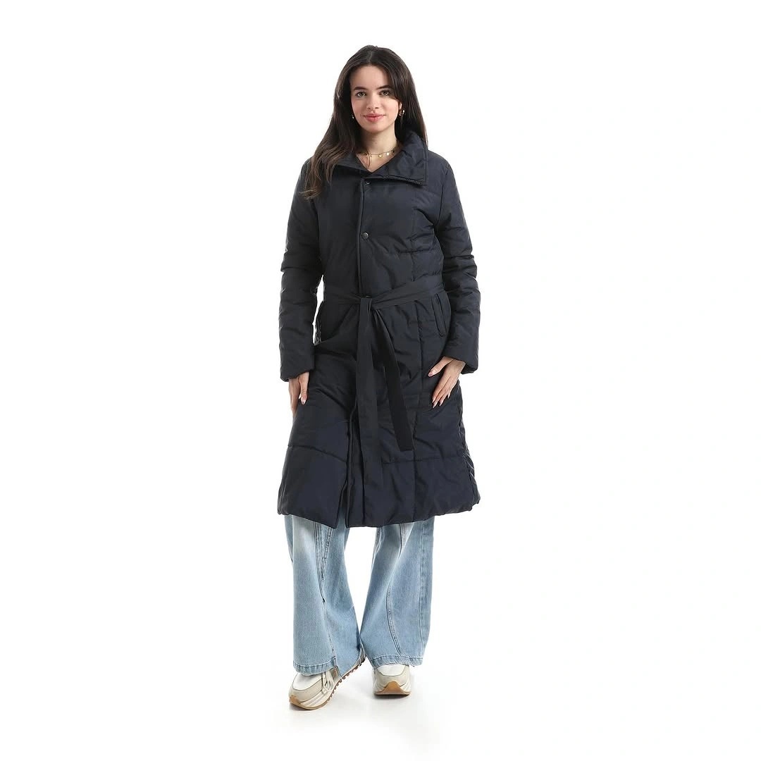 Black belted quilted coat with light blue wide-leg jeans and sneakers