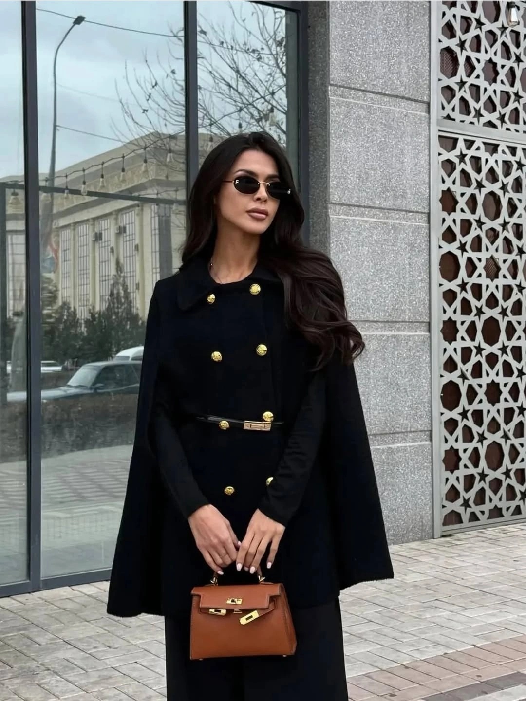 Black cape-style coat with gold buttons and brown structured handbag