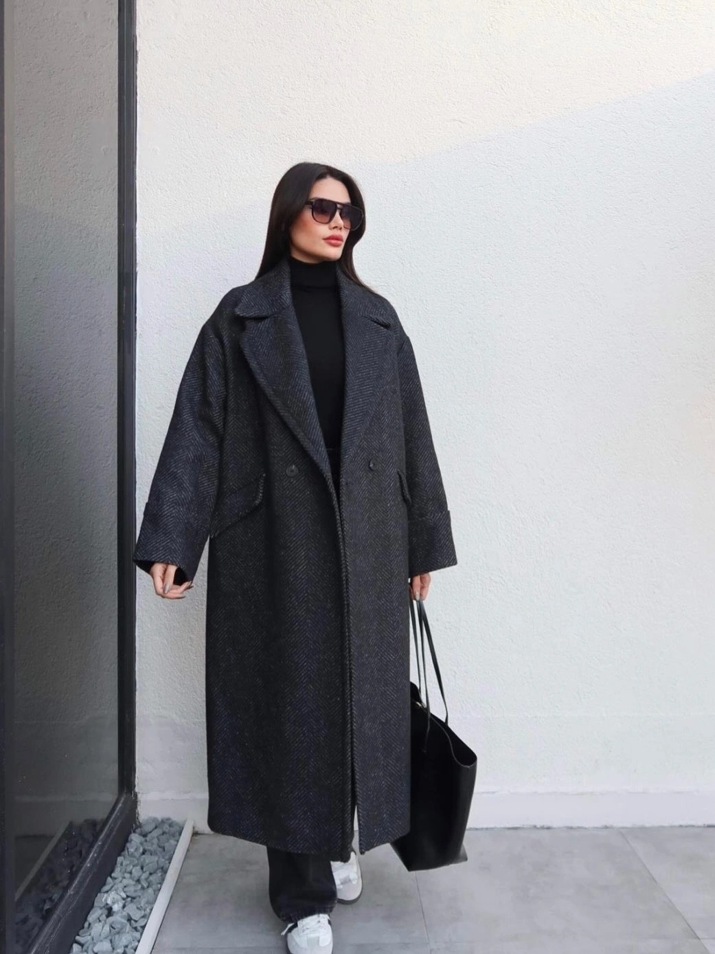 Long charcoal coat with black turtleneck trousers tote and sneakers
