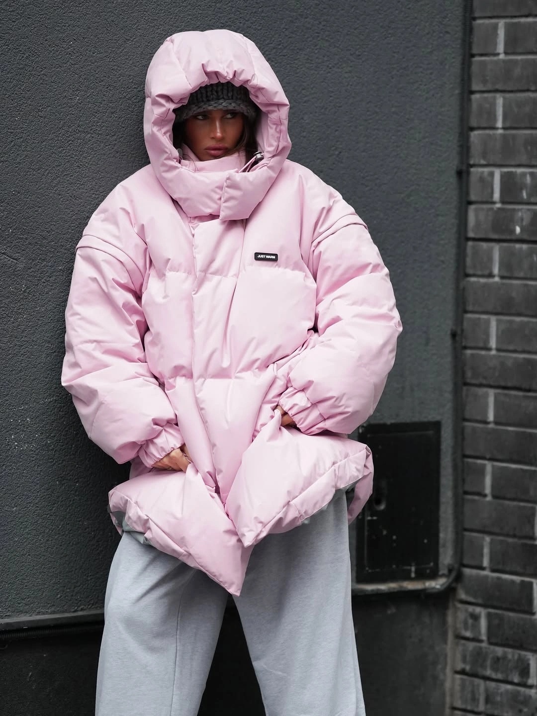 Oversized pale pink hooded down jacket with gray sweatpants