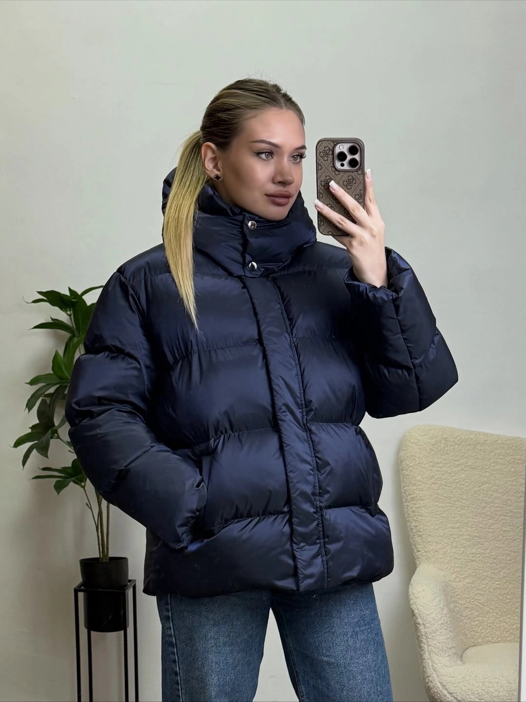 Navy high collar puffer jacket with blue jeans in mirror selfie