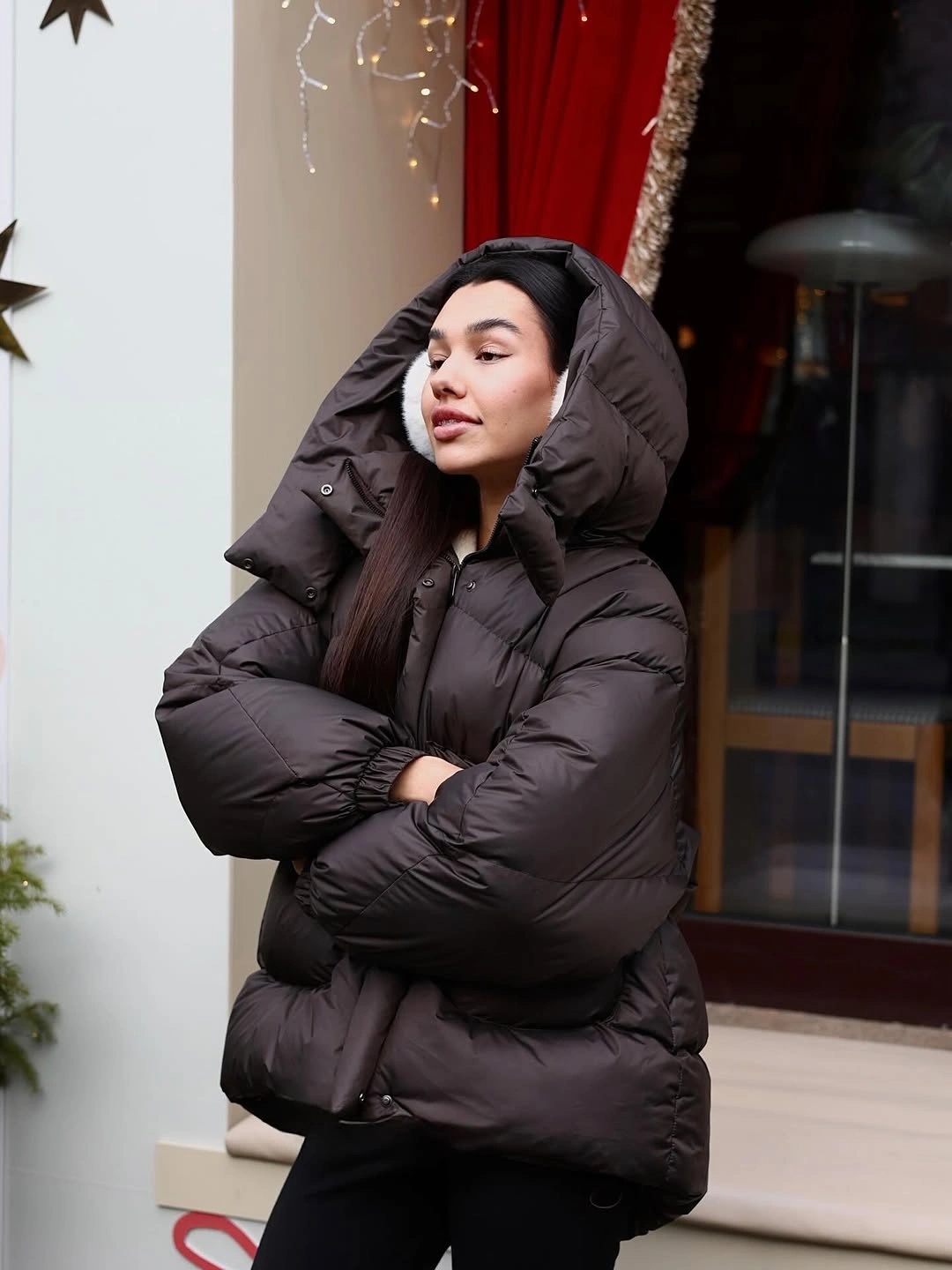 Dark brown hooded puffer jacket with black pants outdoors