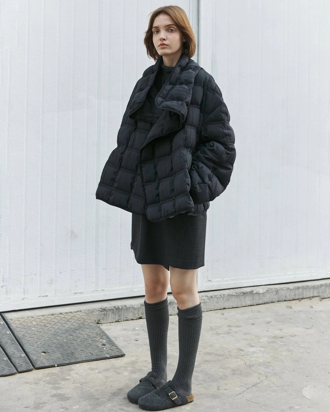 Black puffer jacket with black mini skirt knee socks and loafers