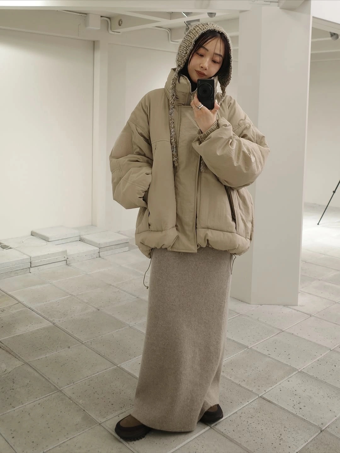 Taupe cropped puffer jacket with long gray knit skirt and beanie