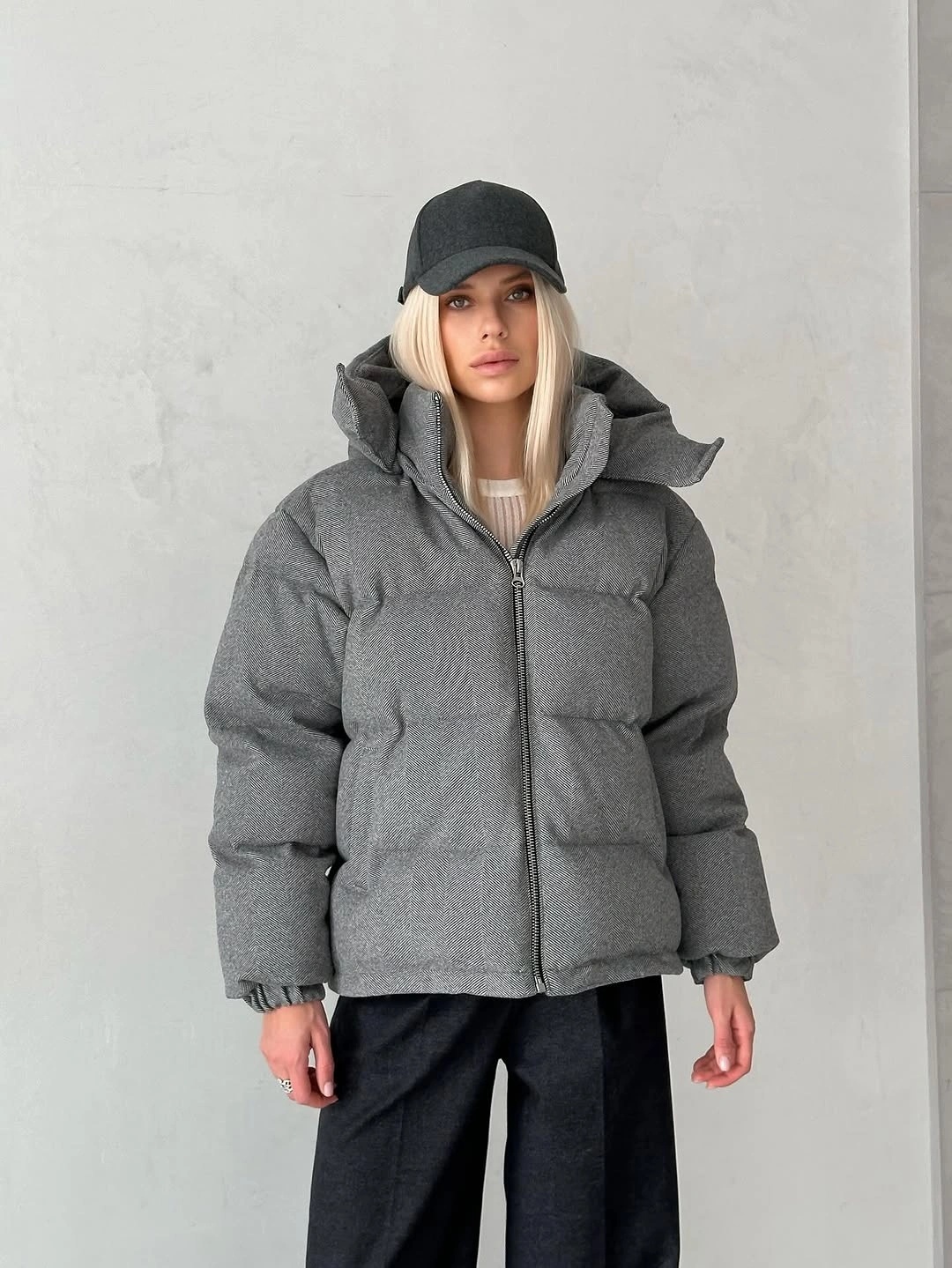 Gray puffer jacket with black cap and wide black trousers