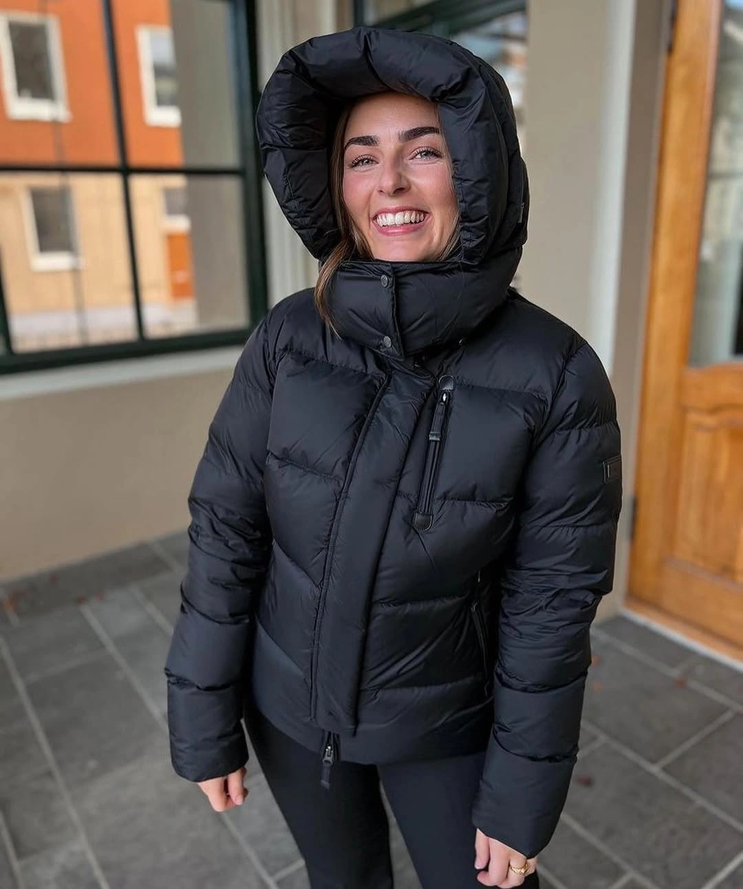 Black hooded puffer jacket with black leggings indoors