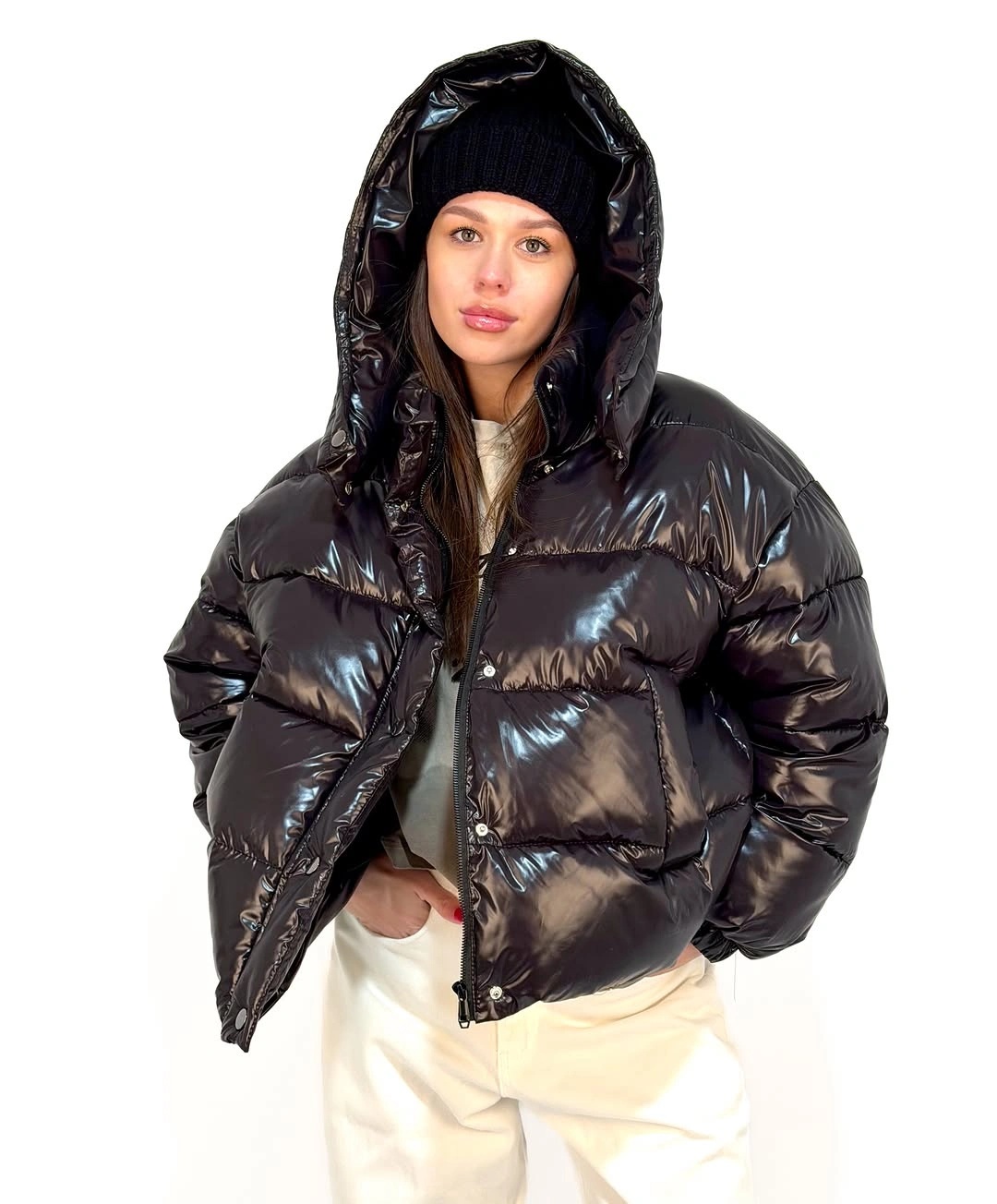 Glossy black hooded puffer with cream trousers and knit hat