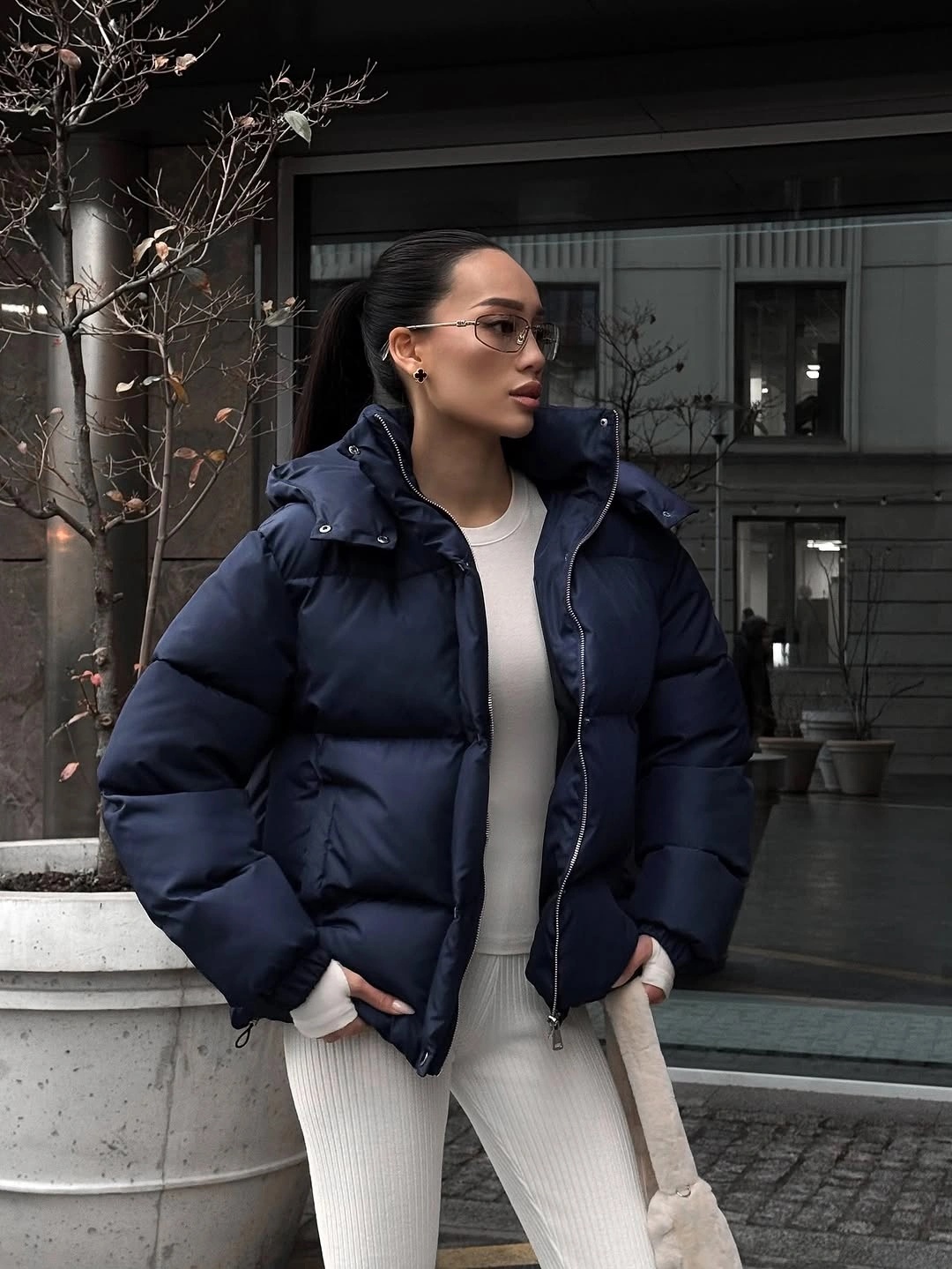 Navy puffer jacket over white top with cream ribbed trousers