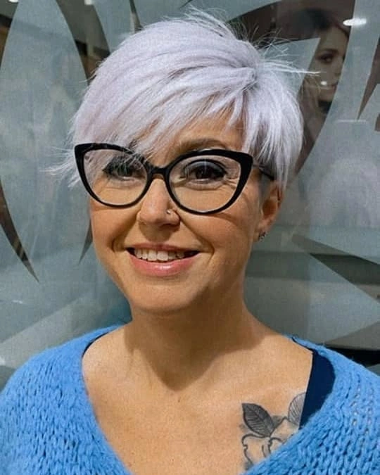 Short silver pixie-like cut with side-swept fringe and cat-eye glasses