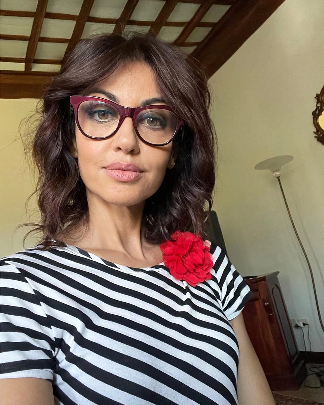 Medium dark-brown wavy hair with glasses and red flower accessory