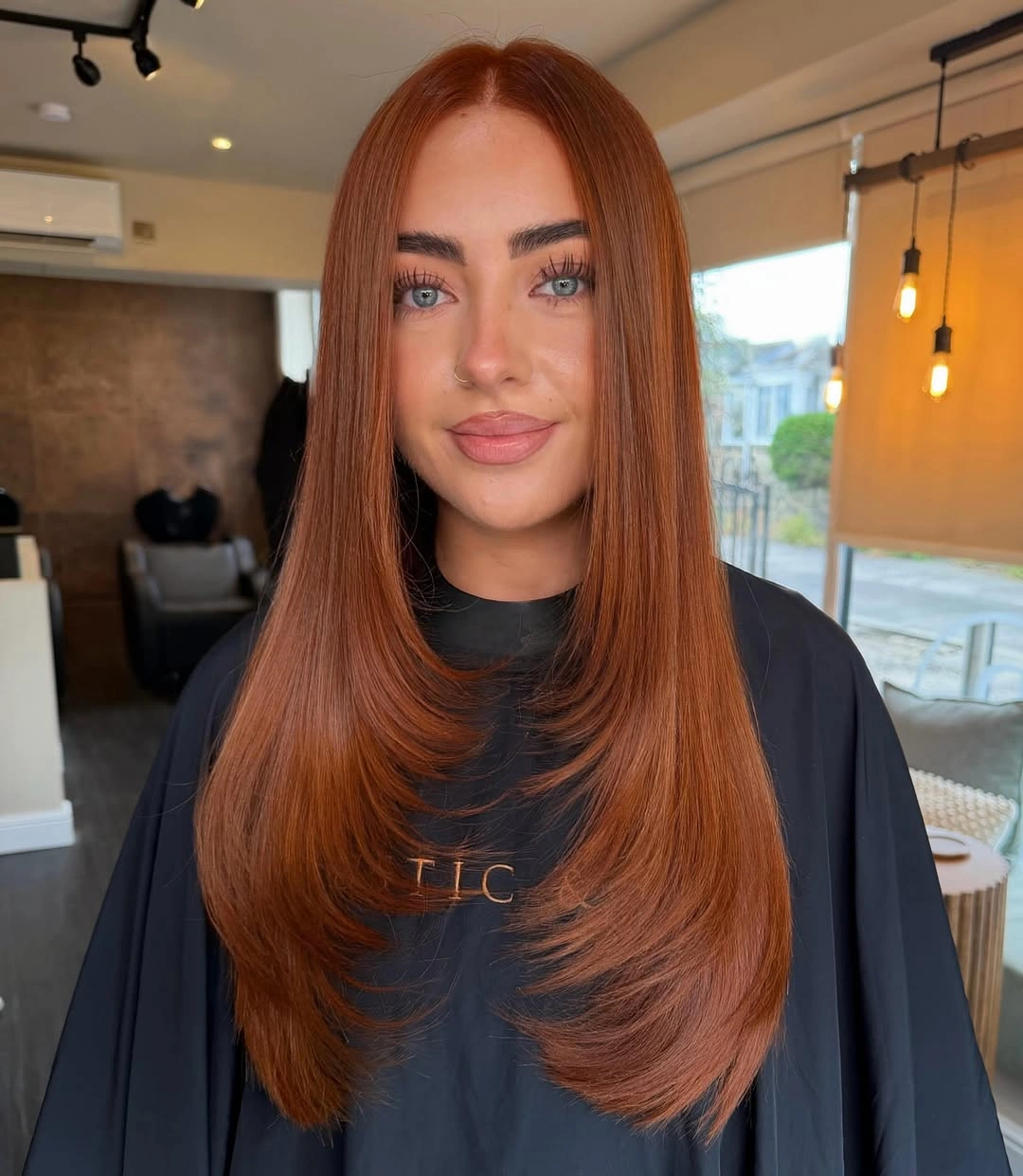 Long auburn hair with center part and curved ends