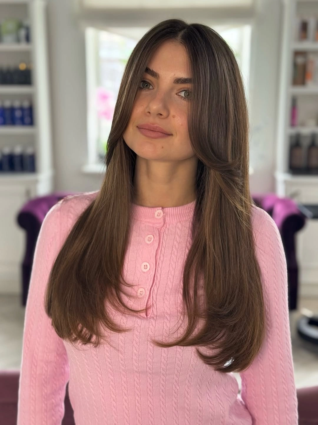Long medium-brown hair with centered part and inward-curving ends