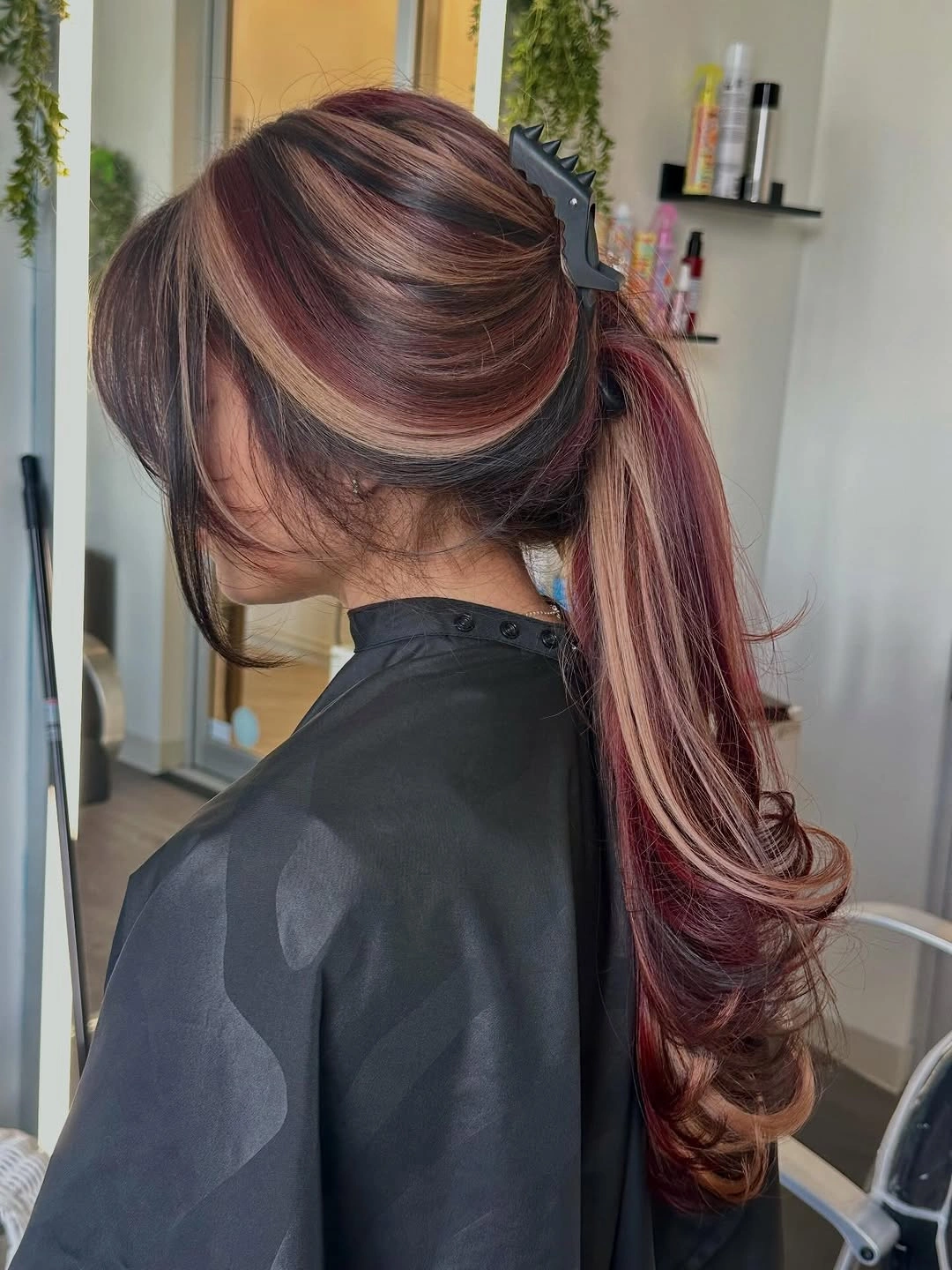Reddish-burgundy ponytail with claw clip and curled tail