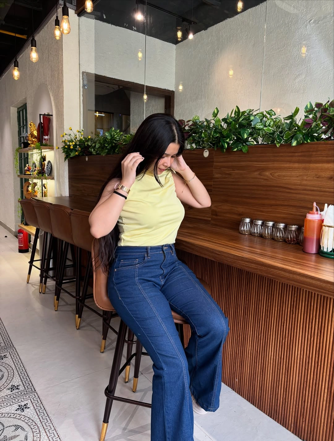 Pale yellow sleeveless top with flared jeans and brown bag