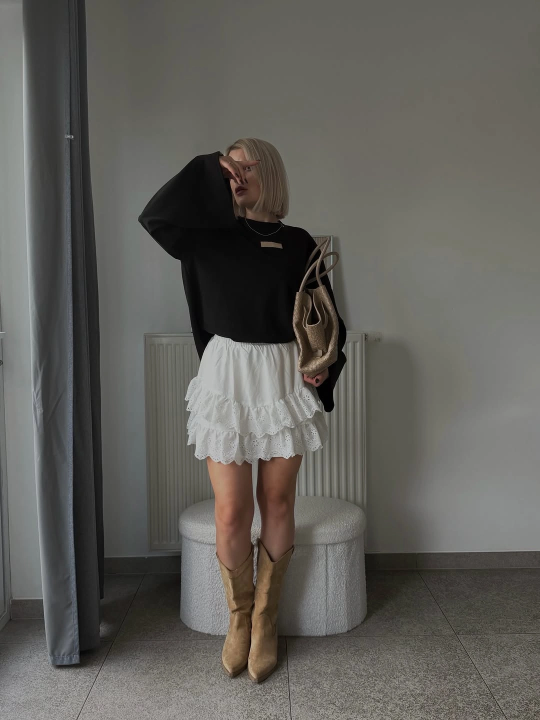Black oversized sweater with white ruffle skirt and tan boots