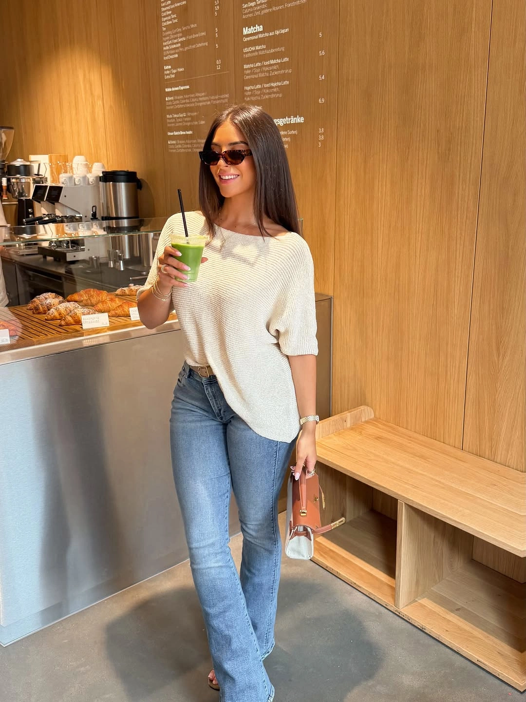 Cream short sleeve knit with flared jeans and tan bag