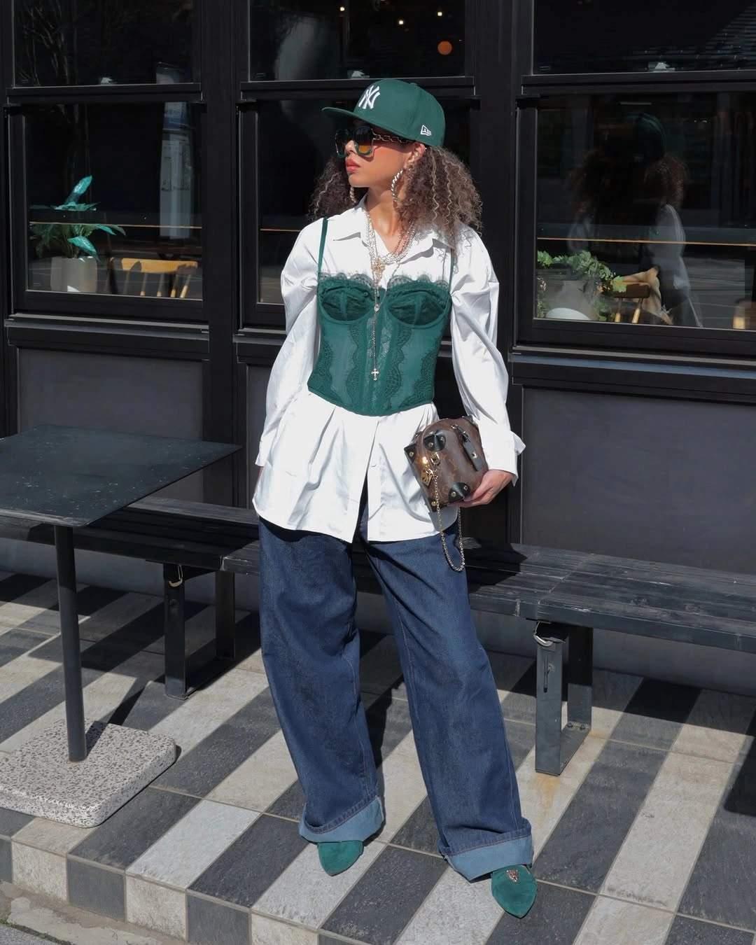 Green cap and corset layer over white shirt and jeans