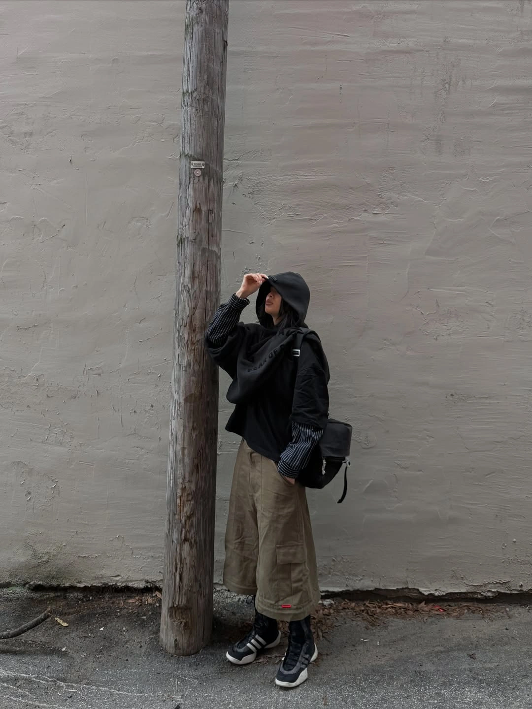 Black hooded top with beige cargo pants and dark sneakers