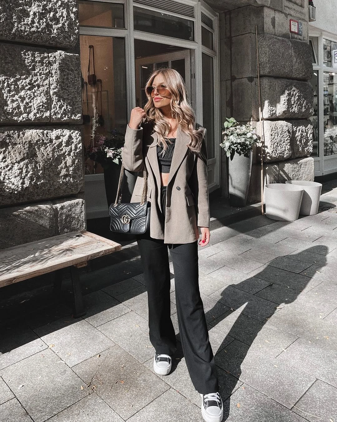 Gray blazer over black outfit with sneakers and shoulder bag