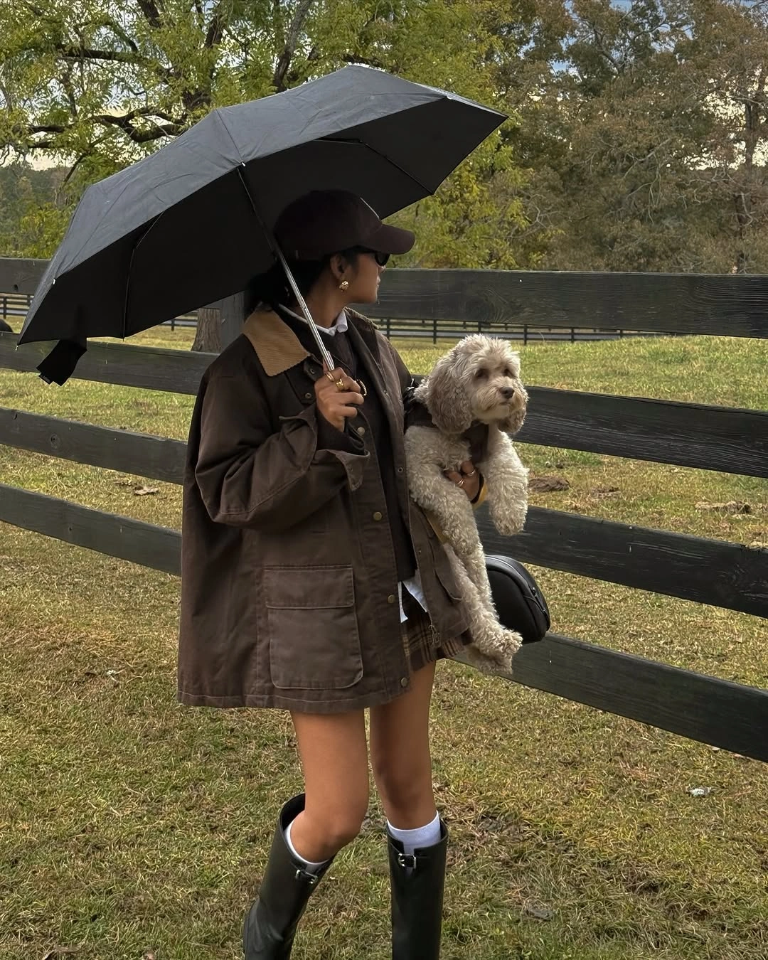 Brown utility jacket with umbrella and tall black boots