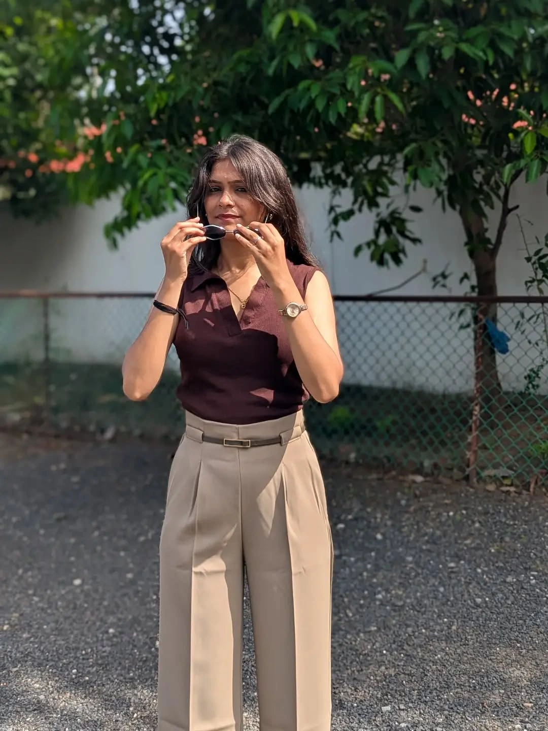 Dark sleeveless top with beige pleated trousers