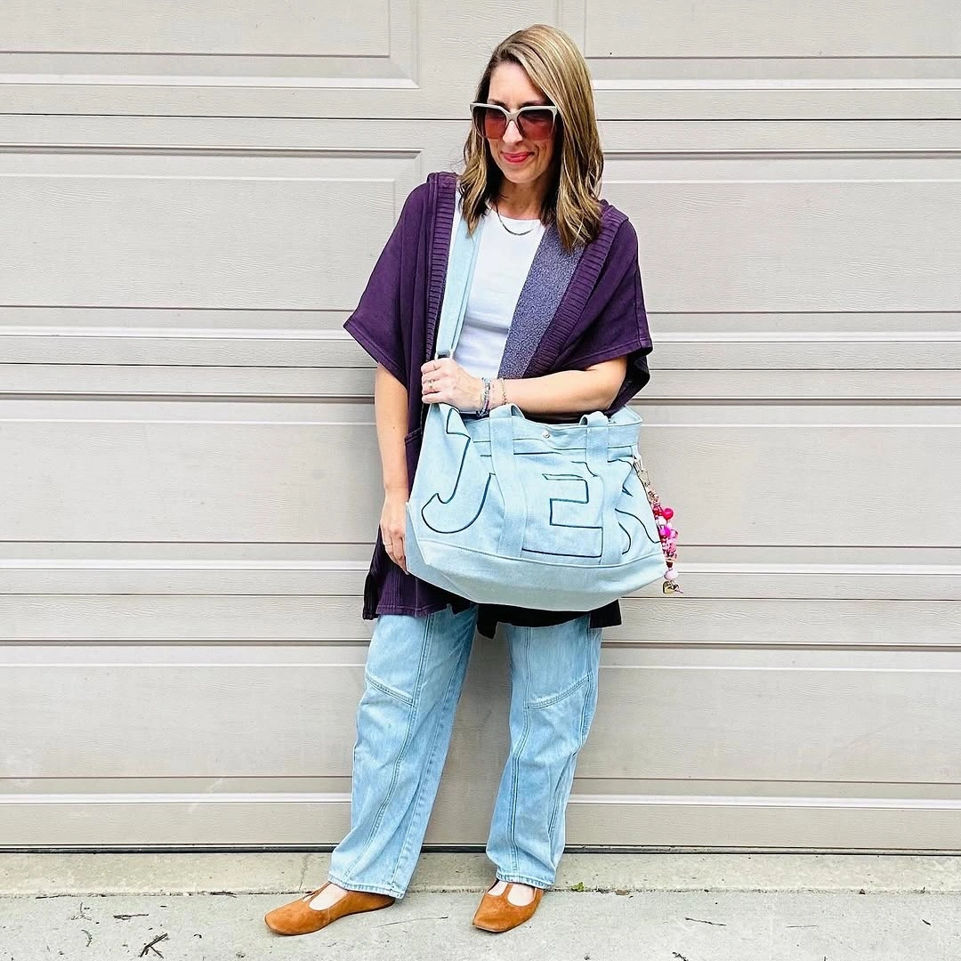 Woman in purple draped layer light jeans and blue tote