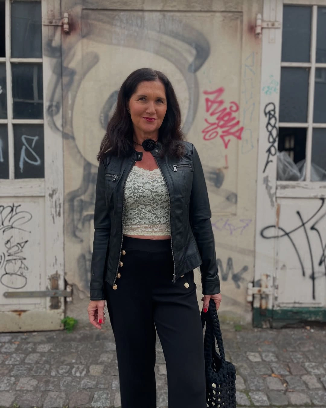 Woman in black moto jacket lace top and wide trousers