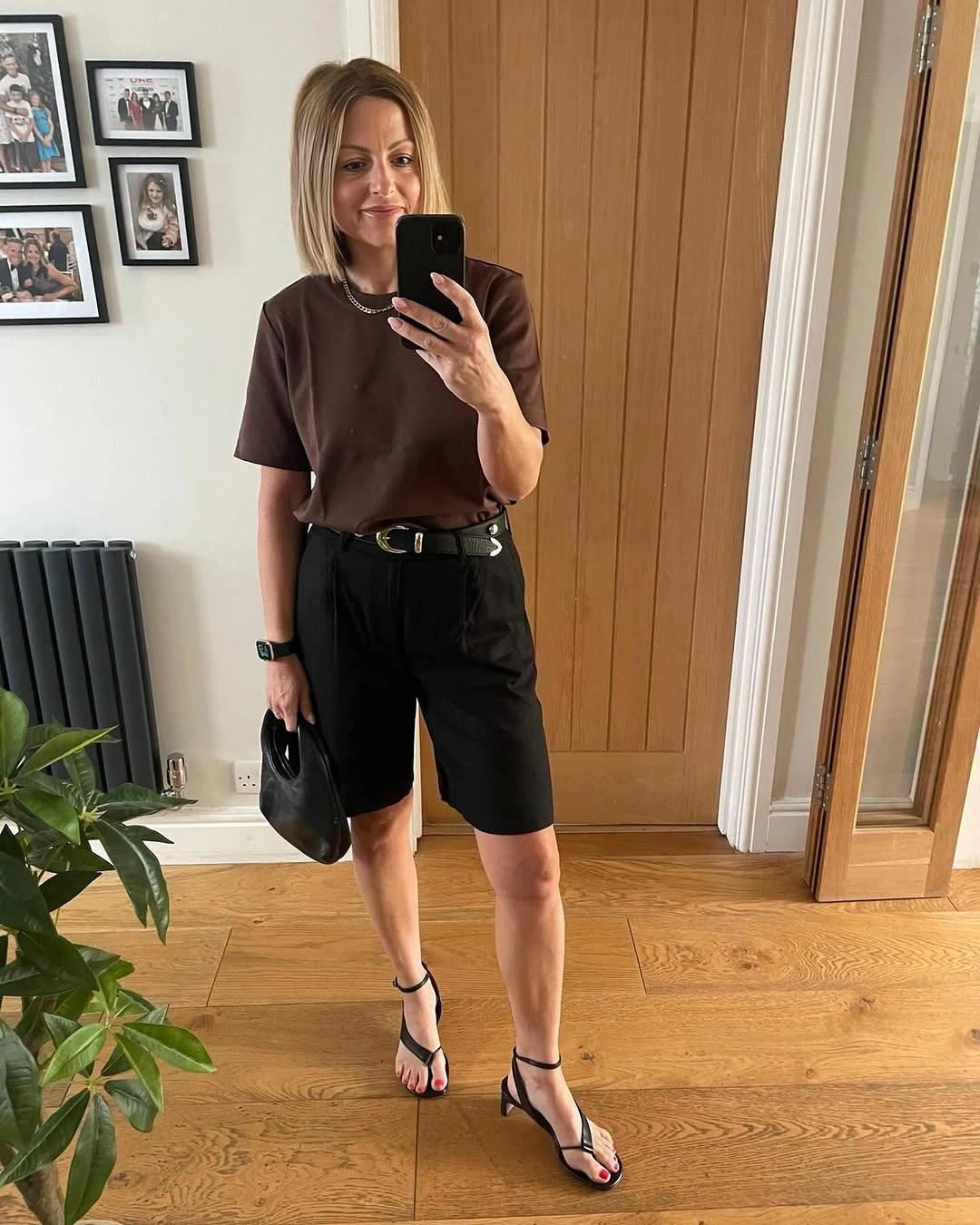Woman wearing brown top black tailored shorts and strappy heels