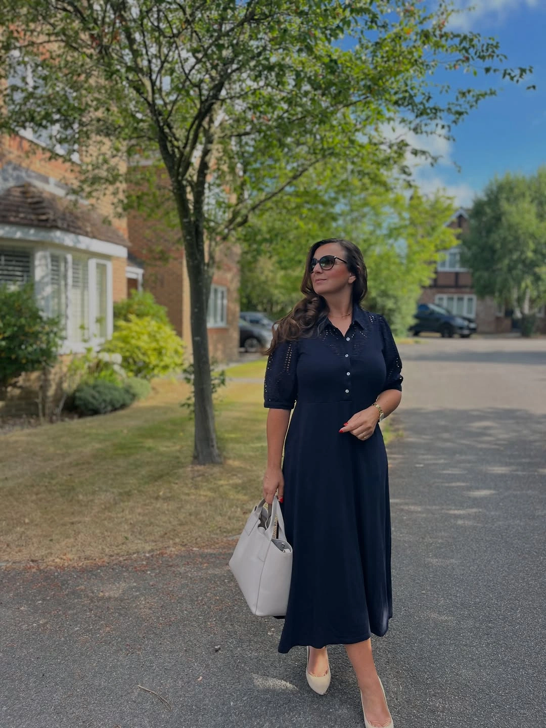Woman in navy collared midi dress with white tote