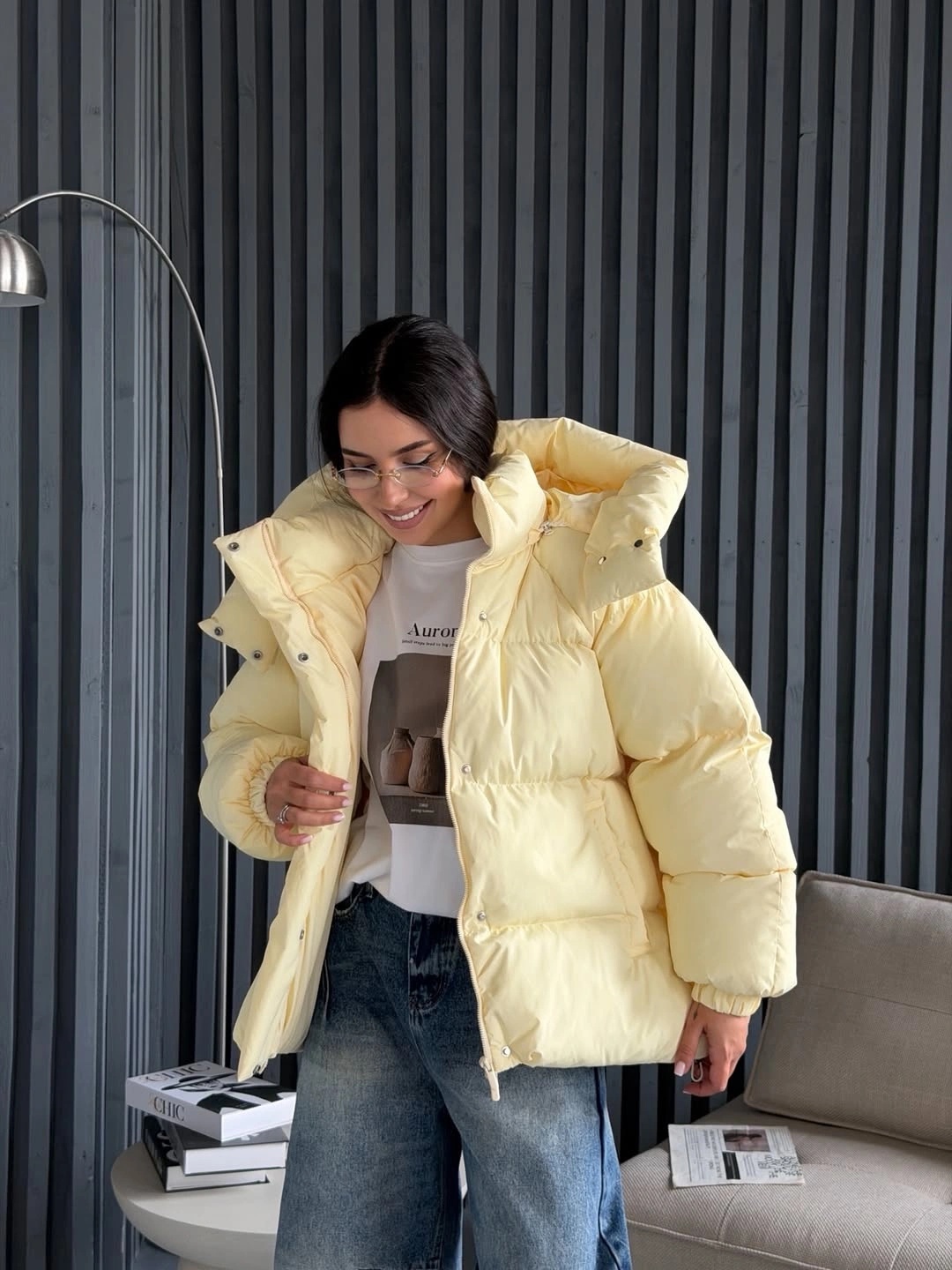 Pale yellow hooded puffer with graphic tee and blue jeans