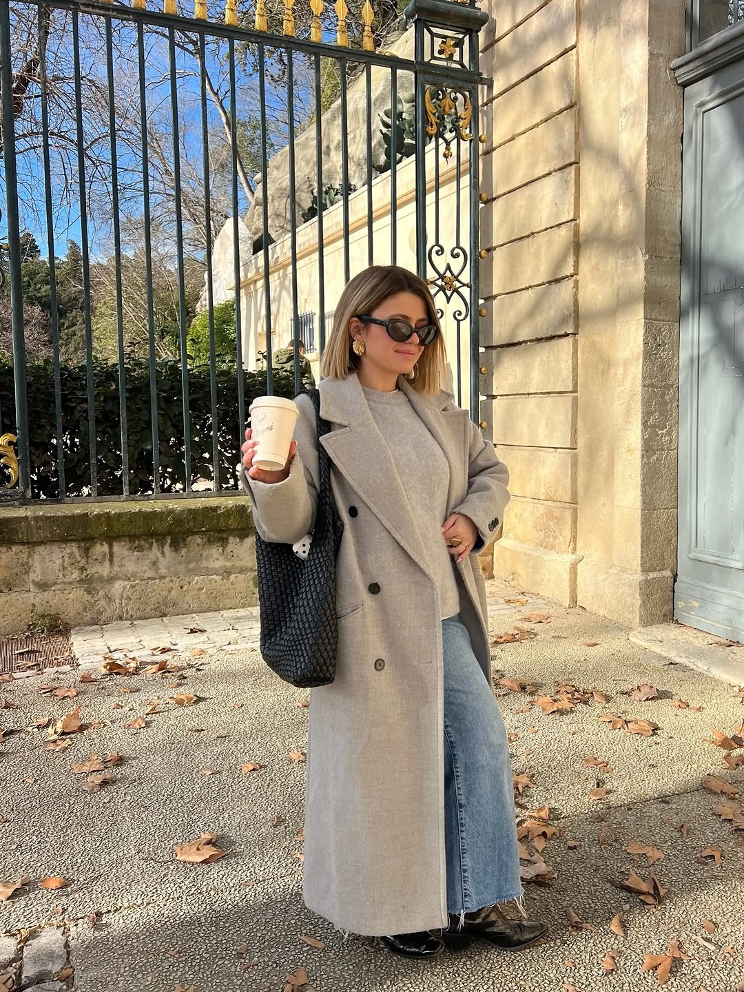Long gray coat with wide blue jeans and dark tote