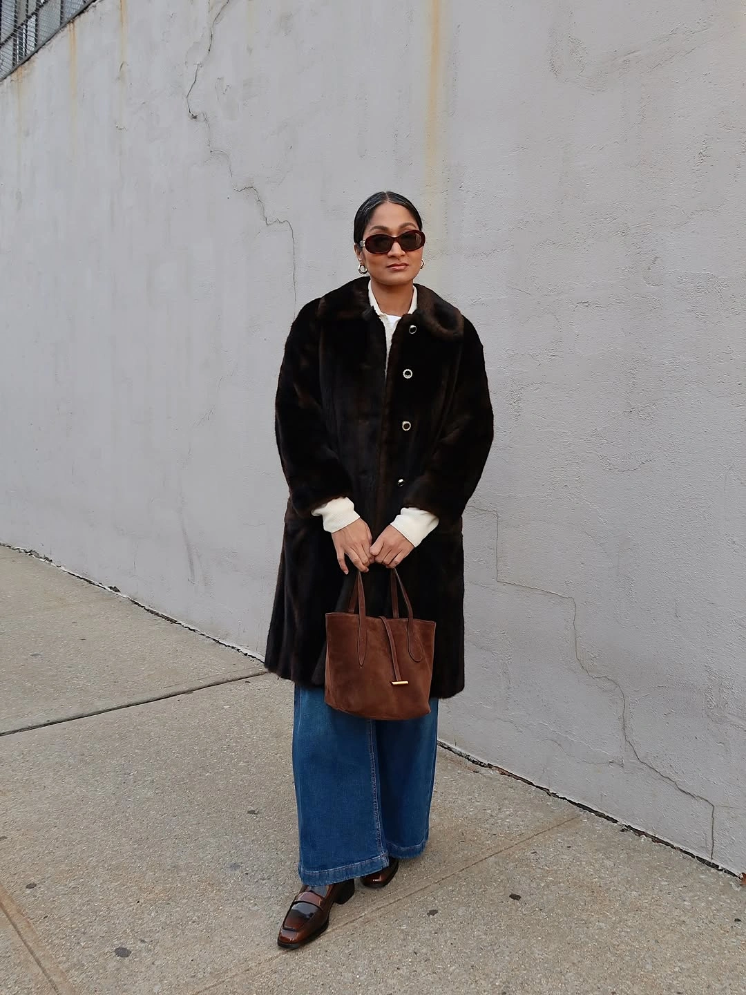 Dark plush coat with blue jeans and brown flat shoes