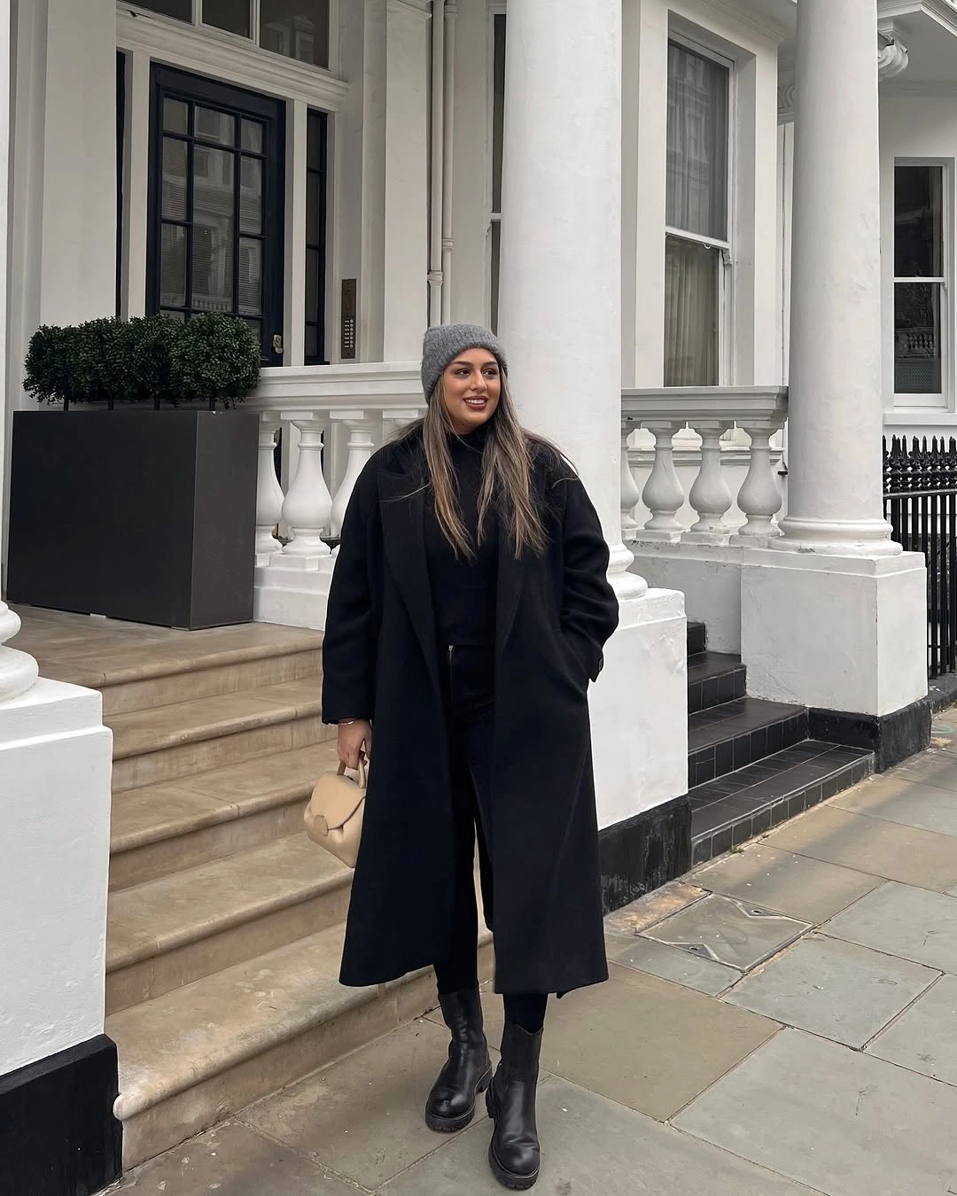 Long black coat with gray beanie and chunky ankle boots