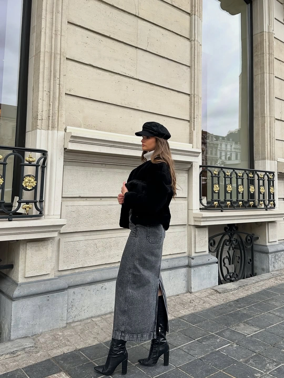 Black fuzzy jacket with long gray denim skirt and boots