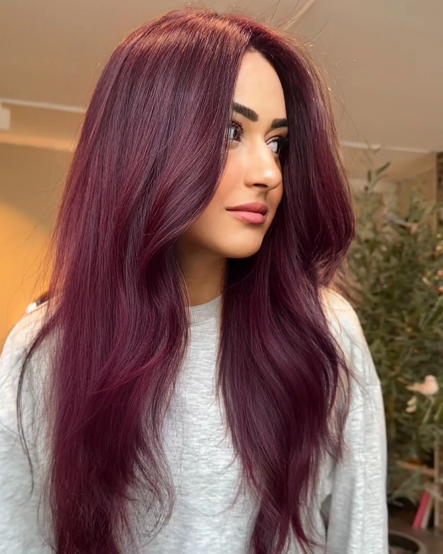 Long smooth berry plum hair with center part and soft waves