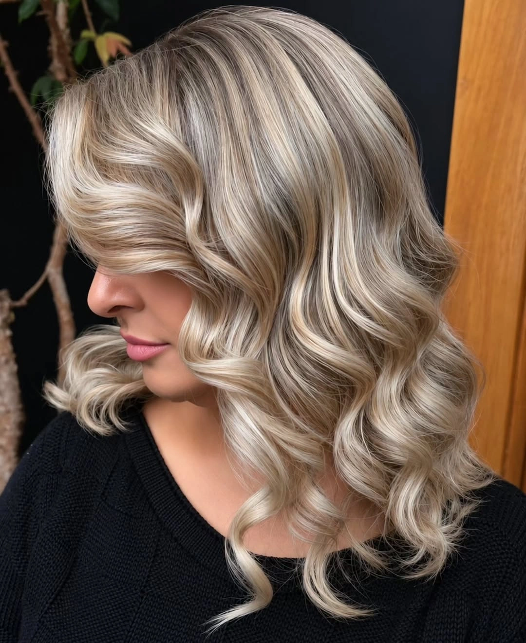 Curled blonde hair with taupe roots and pale cream ribbons