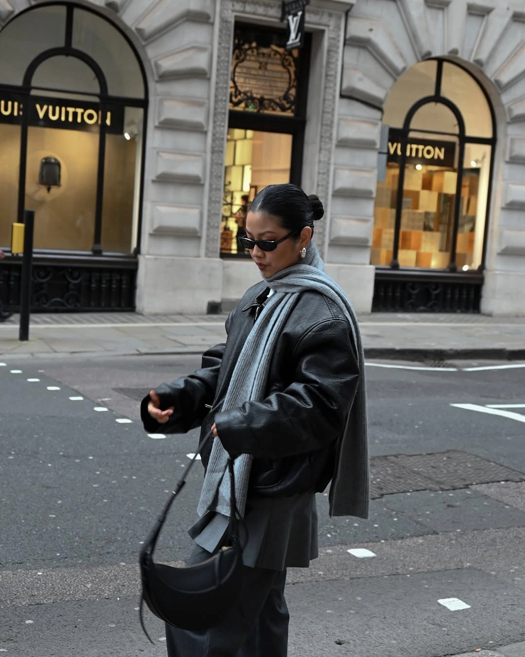 Smooth black jacket with long gray scarf and crescent bag
