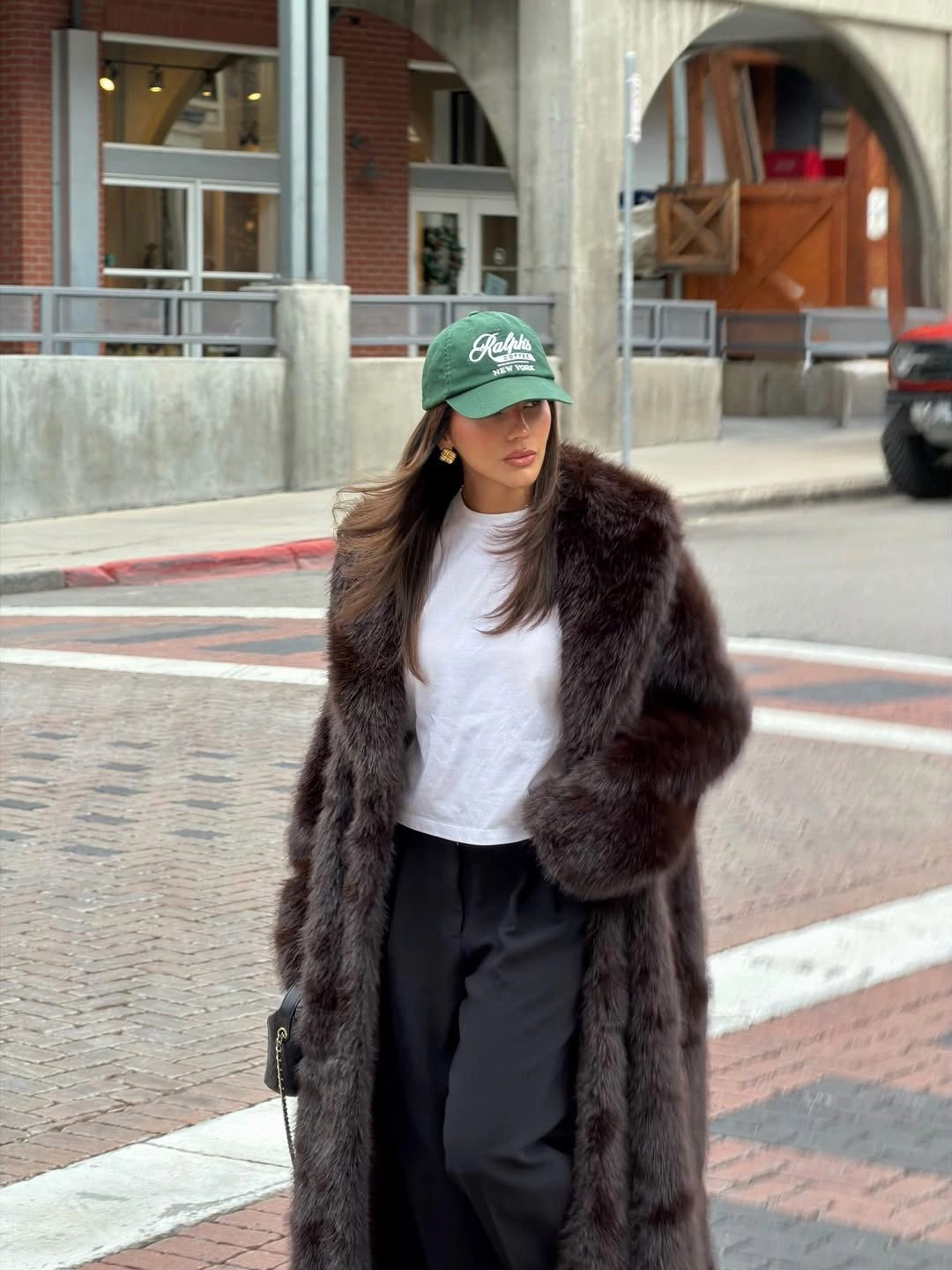 Dark shaggy coat with white tee and green baseball cap