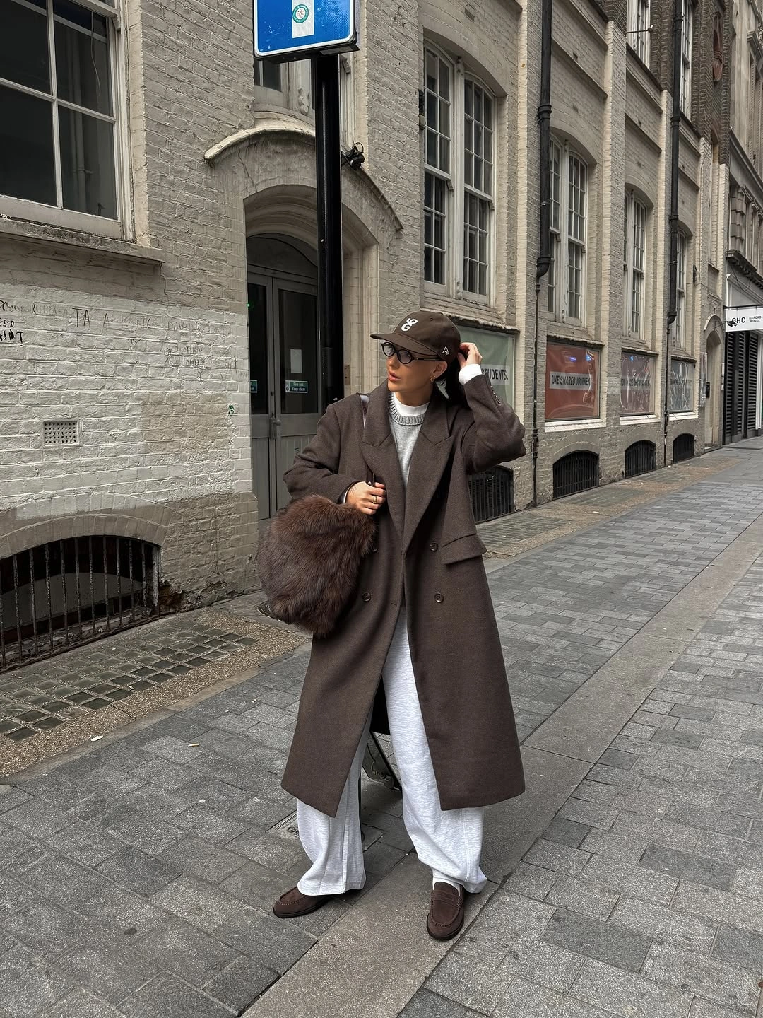 Long brown coat with pale pants, cap and fuzzy bag