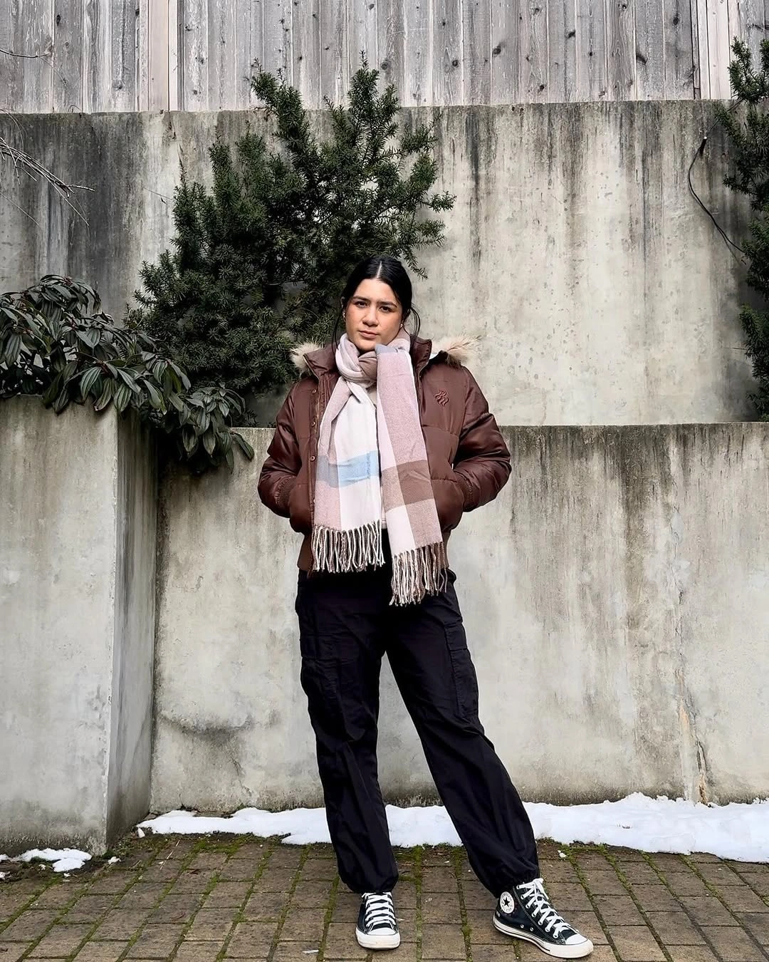 Brown puffer with plaid scarf, black pants and high-top sneakers