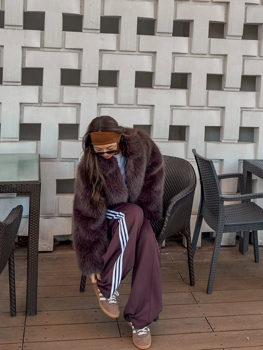 Plum-brown fur-like jacket with maroon striped track pants and sneakers