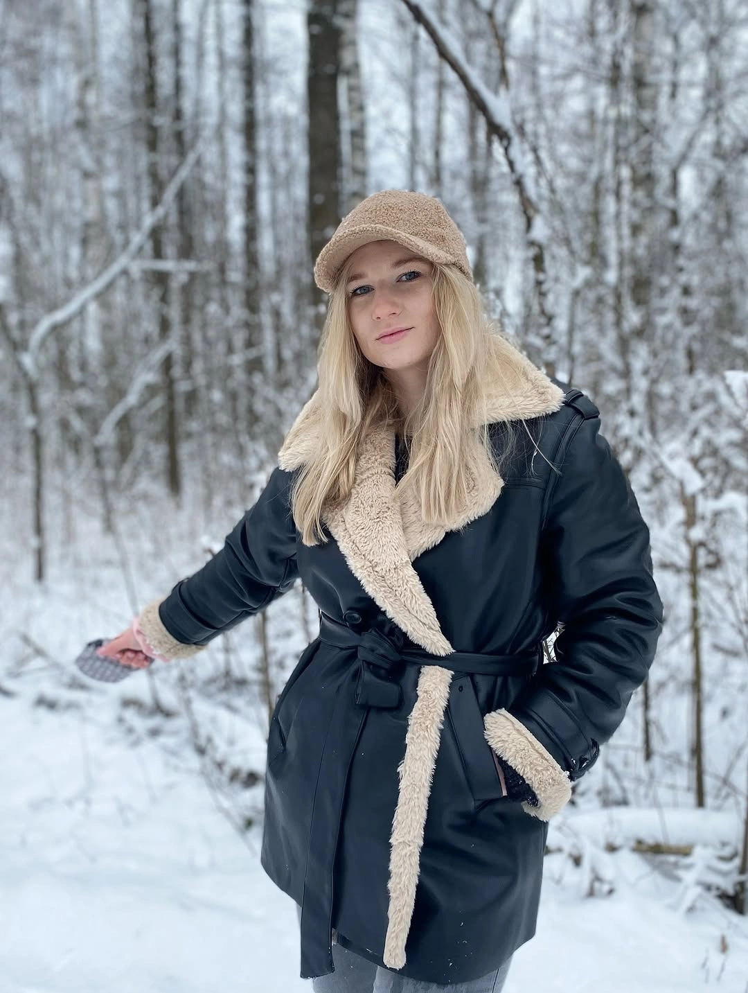 Black leather-look belted coat with cream trim and beige cap