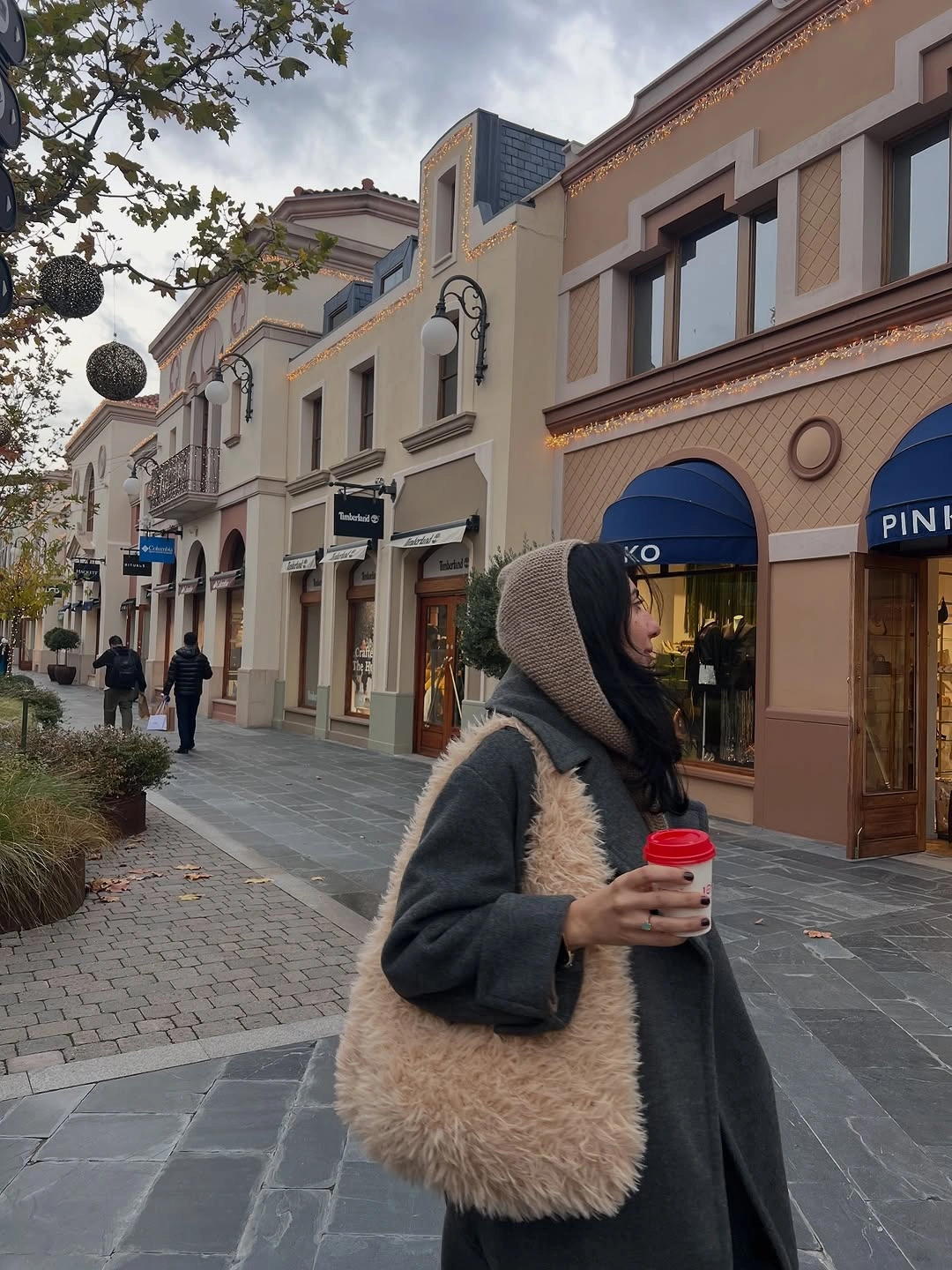 Dark coat with taupe head layer and oversized shaggy beige tote