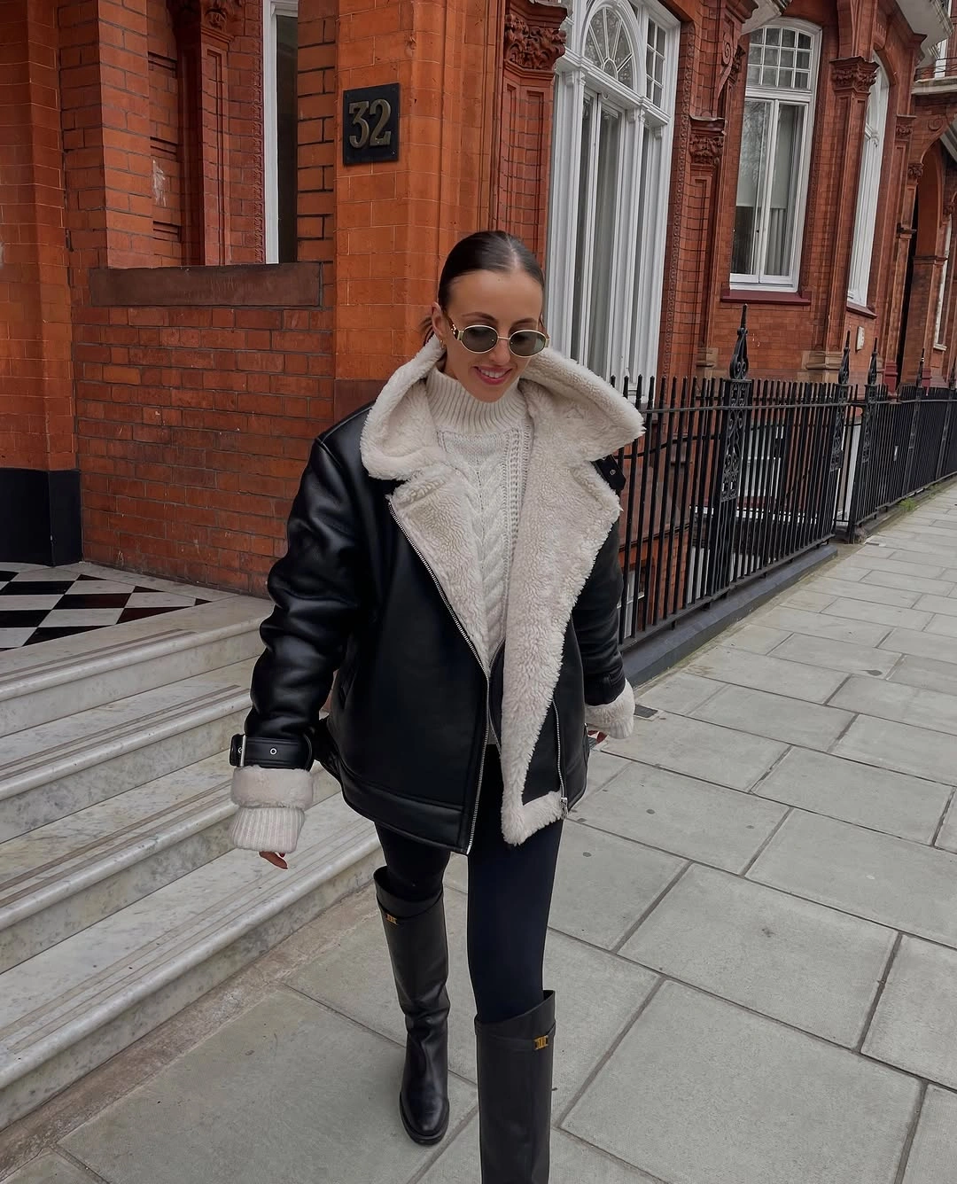 Black leather-look aviator jacket with cream knit and tall boots