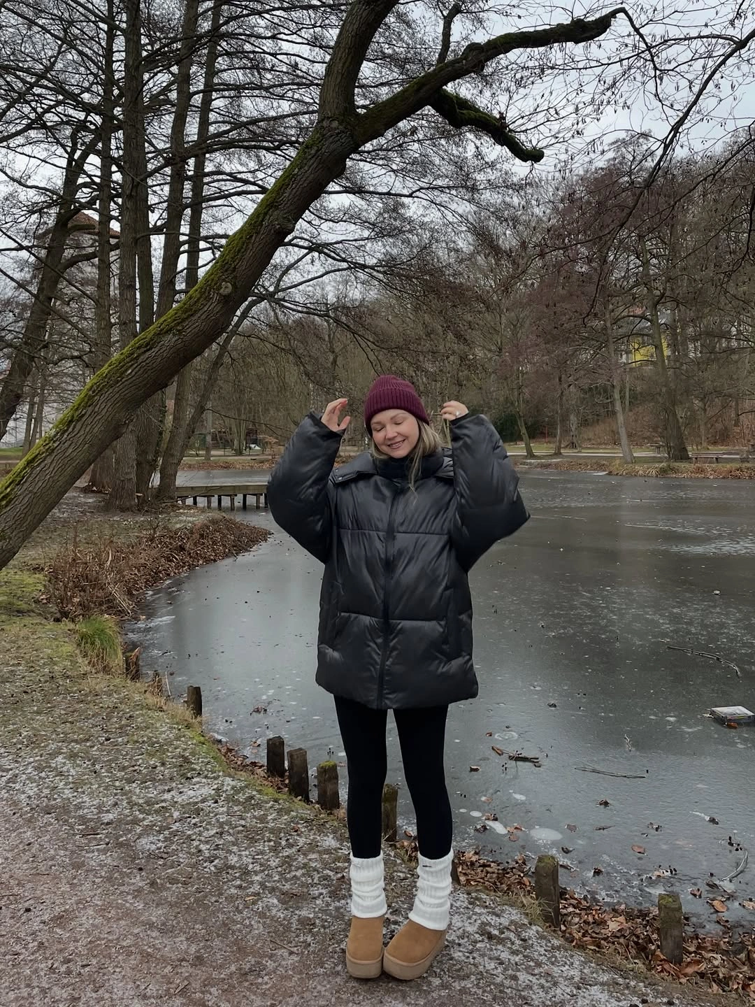 Oversized black puffer-style jacket with burgundy beanie and tan boots