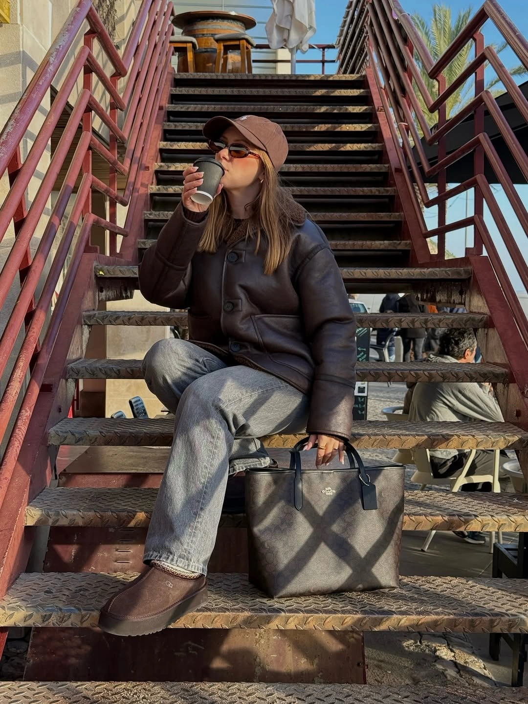 Brown leather-look padded jacket with gray jeans and patterned tote